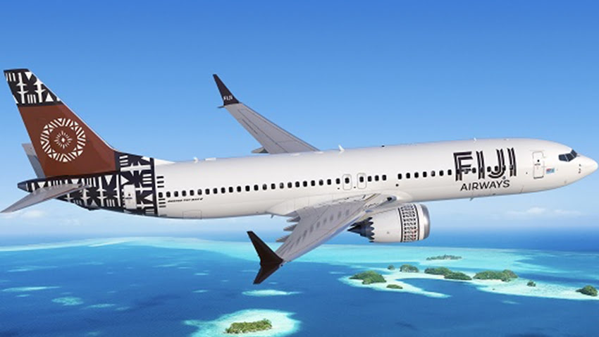 Fiji Airways airplane flying over turquoise ocean and small tropical islands,
