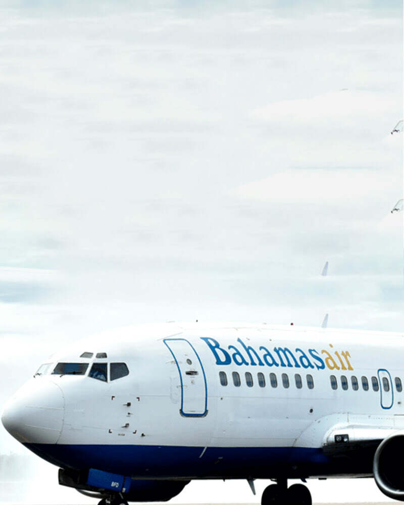 A BahamasAir airplane on the tarmac under a cloudy sky, showcasing its logo prominently on the fuselage