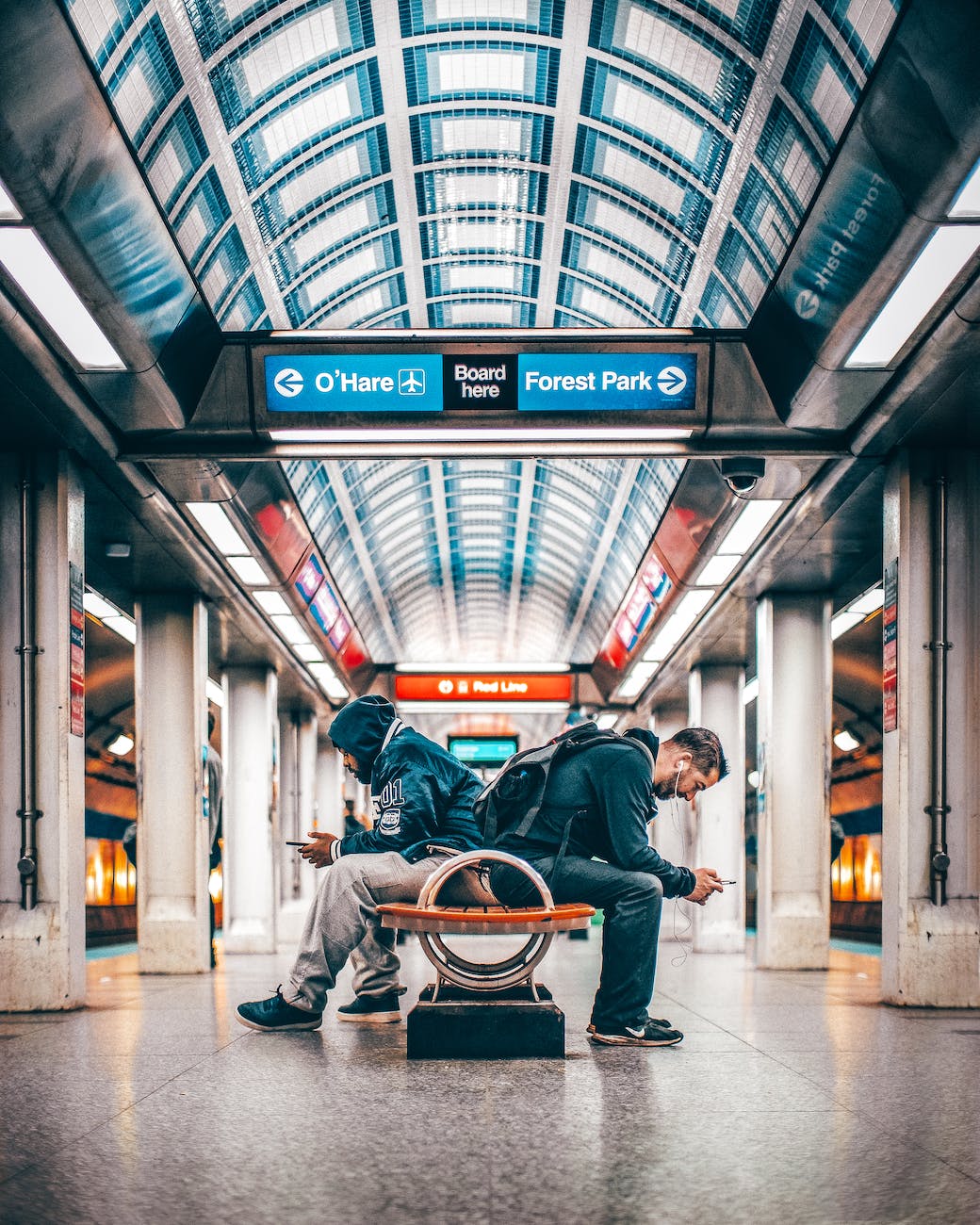 two men sitting on bench inside a station