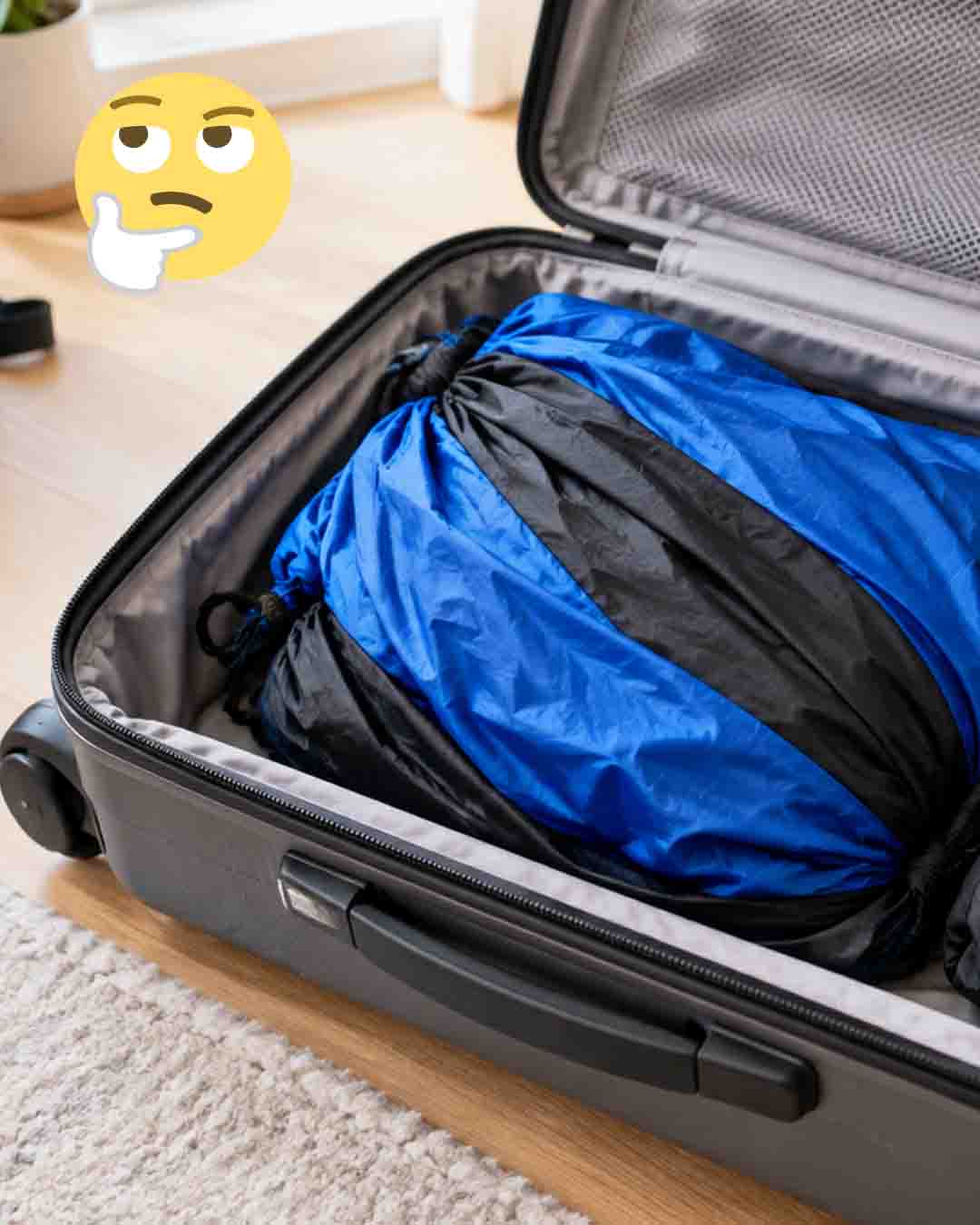 Blue and black camping hammock packed in an open suitcase with straps and carabiners