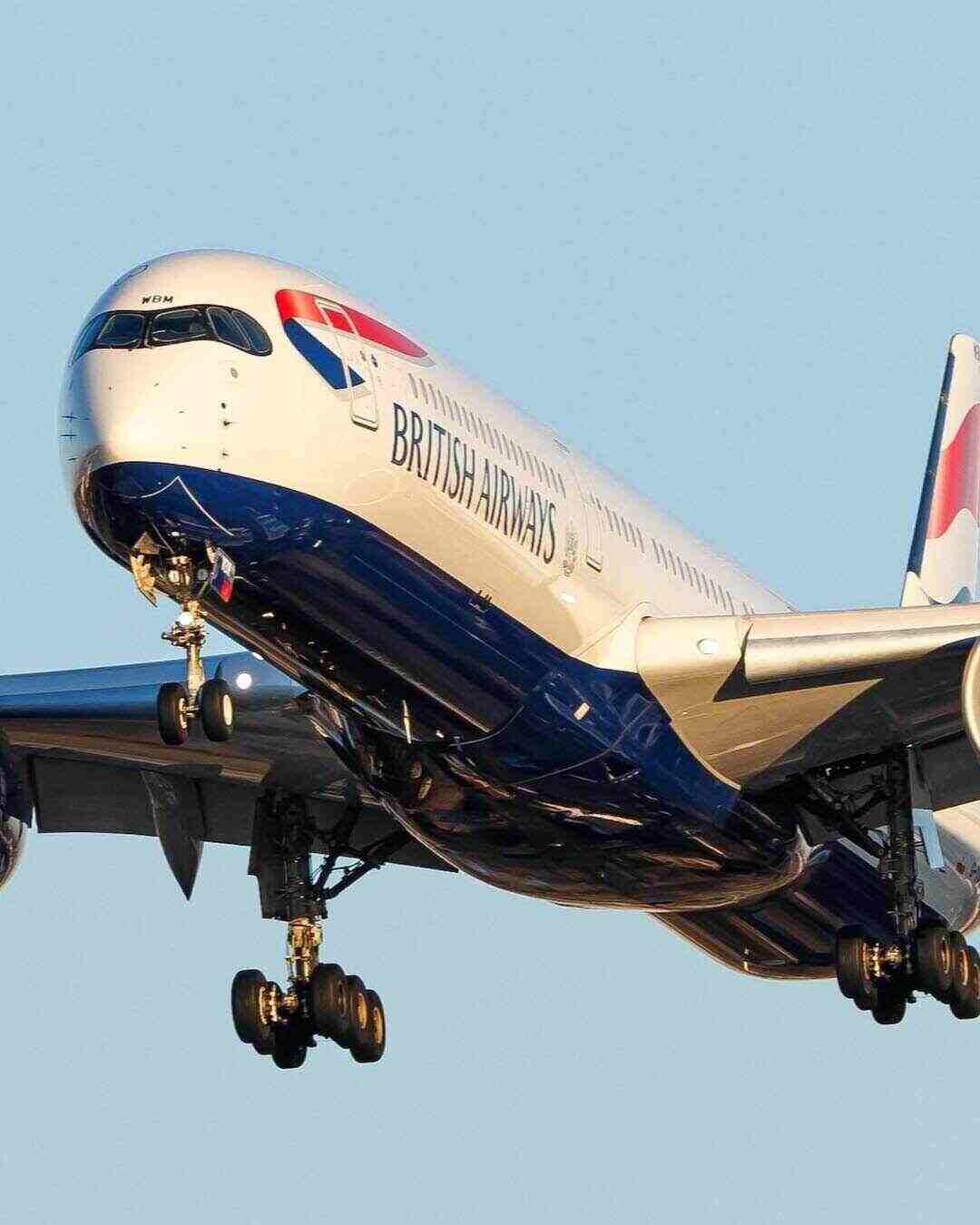 British Airways airplane descending with landing gear down against a clear blue sky