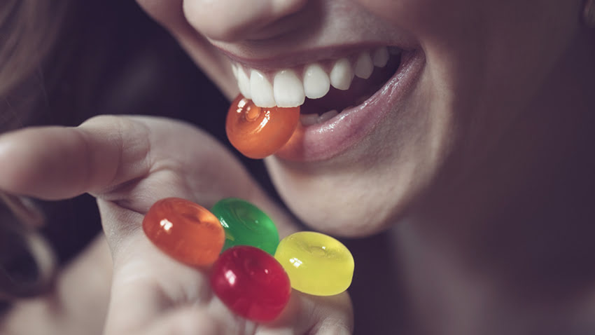 Close-up of a woman smiling while holding colorful hard candies, perfect for travel.