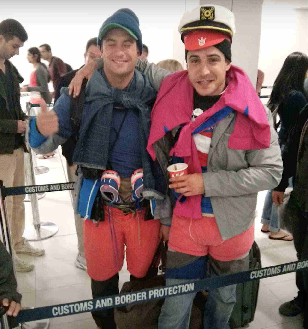 Two travelers at airport wearing multiple layers of clothes and hats to avoid Spirit Airlines oversized baggage fees. 
