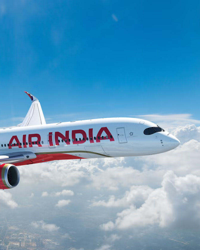  An Air India airplane flying above the clouds under a bright blue sky