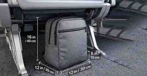 Carry-on backpack under an airplane seat with labeled size measurements